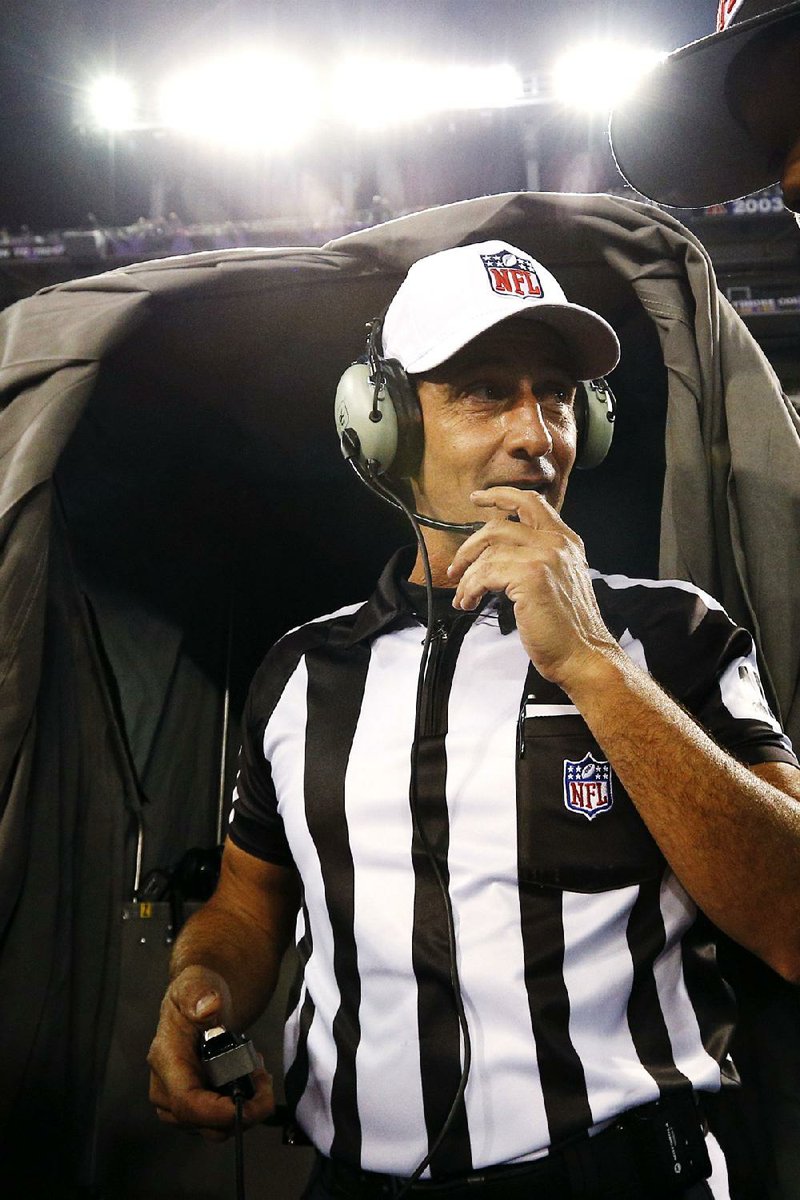 Referee Gene Steratore talks to booth officials before Thursday’s NFL game in Baltimore. It was the first game this season with the regular officials after the lockout ended late Wednesday night. 