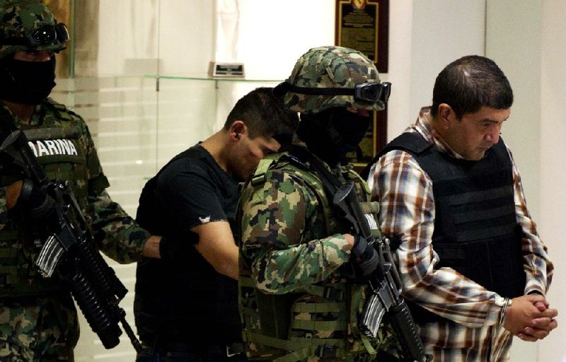 The purported leader of a faction of the violent Zetas cartel, Ivan Velazquez Caballero, (right) is taken to be presented Thursday to the media at a navy center in Mexico City. 