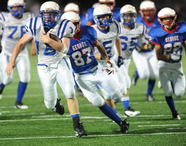 Bradon Mabry, left, Rogers High freshman running back, carries the ball Thursday as George Junior High’s Jesus Perez pursues in the first half at Jarrell Williams Bulldog Stadium in Springdale. 