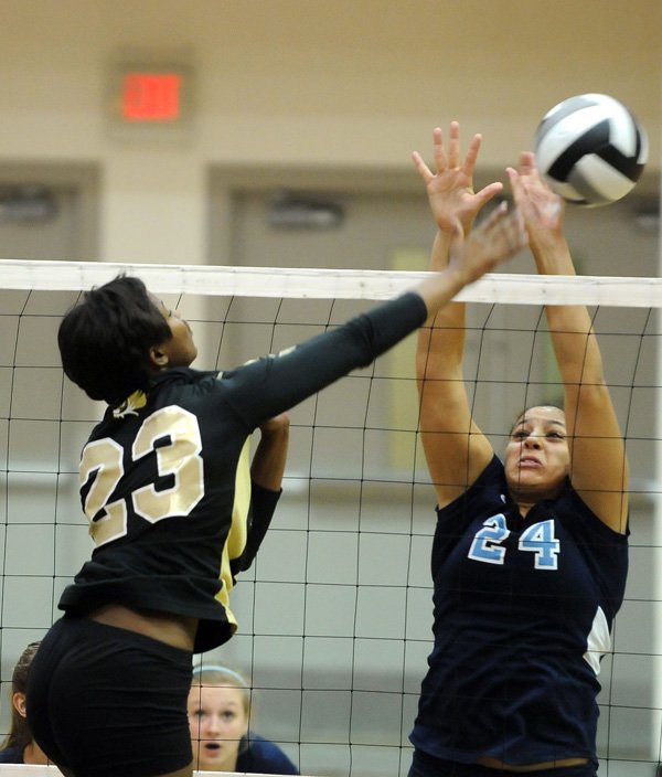 Ariel Hornsby, left, a Bentonville junior, spikes the ball against Springdale Har-Ber senior Tayleah Neal during the first set Thursday at Tiger Gym in Bentonville. 