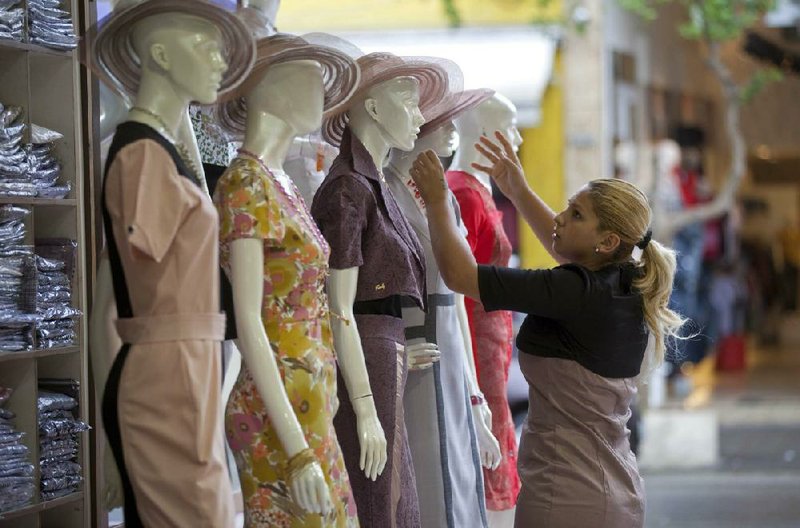 A saleswoman adjusts mannequins wearing “Moda Evangelica” — so-called evangelical fashion — in a Sao Paulo shop. Brazil is known for its short and sexy apparel, but there’s a growing market for clothing that is a bit more modest. 