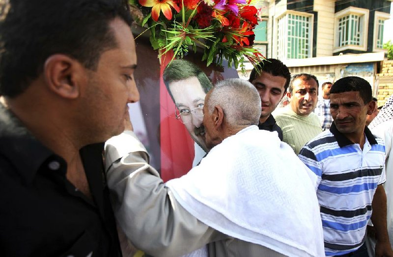 A relative of former Basra governor Mohammed al-Wailie kisses his poster Friday during his funeral in Basra, Iraq. Al-Wailie was shot dead earlier in the day as he was driving. 