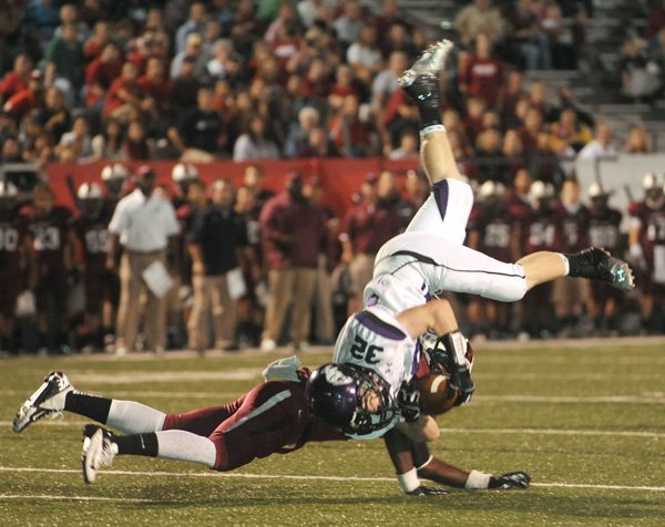 Cole Harris, Fayetteville senior receiver, is upended Friday as he is hit by Springdale junior Qua Rose in the first half at Jarrell Williams Bulldog Stadium in Springdale. 