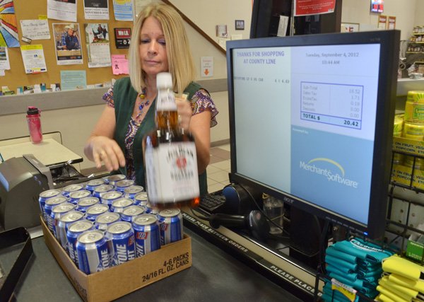 Barbara Rasmussen of County Line Liquor checks out a customer in Springdale. “I think Benton County will vote for alcohol,” store owner Jim Phillips said. “That will have a big impact on Springdale taxes.” 