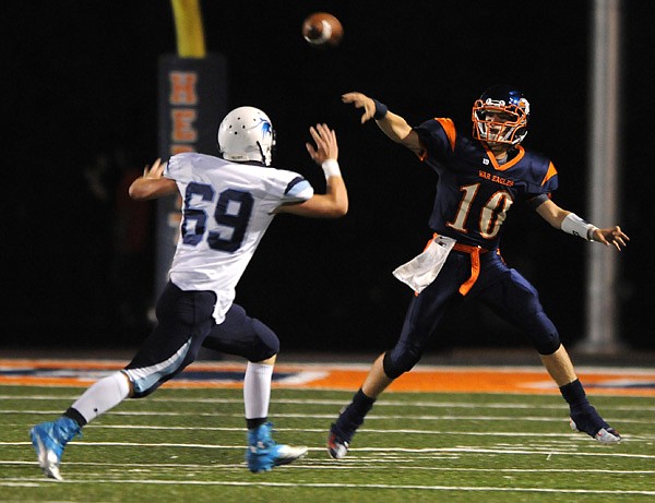 Josh Qualls, right, Rogers Heritage, passes the ball Friday over Chase Bowers of Springdale Har-Ber at Gates Stadium in Rogers. 