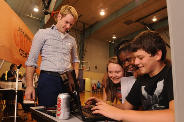 Josh Franks, with the Arkansas Crisis Center, left, watches as McKayla Perrin, 12, Carrissa Jackson, 13, and Kodie McDaniel, 13, Holt Middle School seventh-graders ask questions Monday via computer to someone at the center during the Charity Fair at the school in Fayetteville. The students will learn about the charities in order to research and try to get their class to support one. Each seventh-grade class will choose a charity to which to donate. This is a part of the new curriculum about argumentative writing.