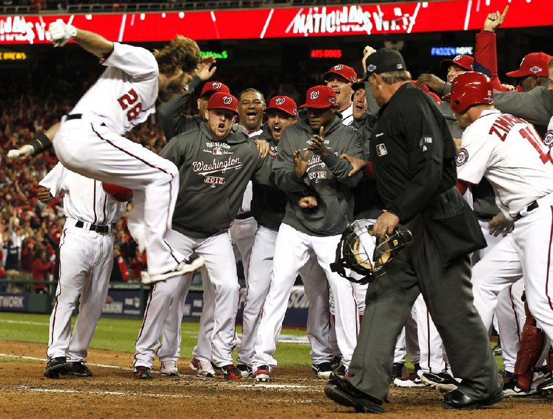 Washington’s Jayson Werth (left) leaps toward home plate and is greeted by teammates after hitting the game-winning home run in the bottom of the ninth inning to give the Nationals a 2-1 victory over the St. Louis Cardinals on Thursday in Washington. 