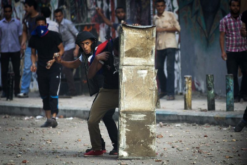 A protester hurls a stone Friday in Cairo’s Tahrir Square during clashes between backers and opponents of Egyptian President Mohammed Morsi. More than 100 people were injured in the first such violence since the Islamist president assumed power in late June.