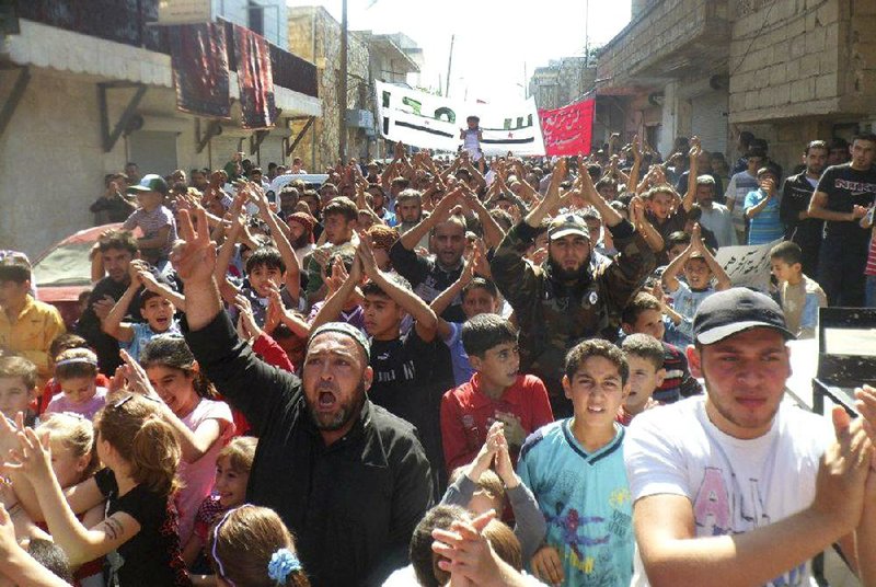 Anti-government protesters march Friday in Sarmada in Syria’s northern Idlib province.

