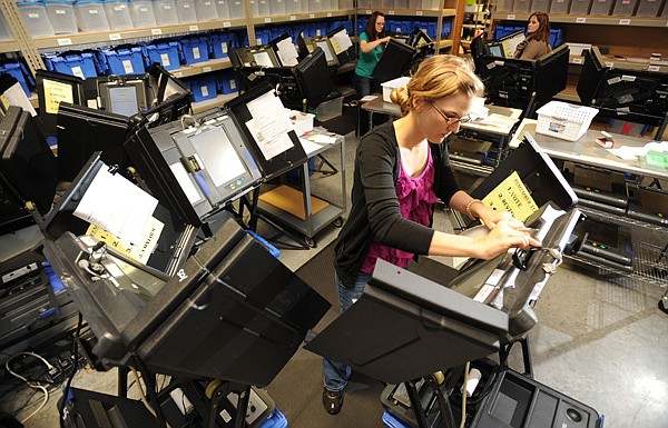 Laura Shepard-Johnson, a field technician for the Washington County Election Commission, works Monday with other technicians testing and preparing electronic voting machines for the early voting period for November’s general election at the commission’s facility at the county’s south campus in Fayetteville. 