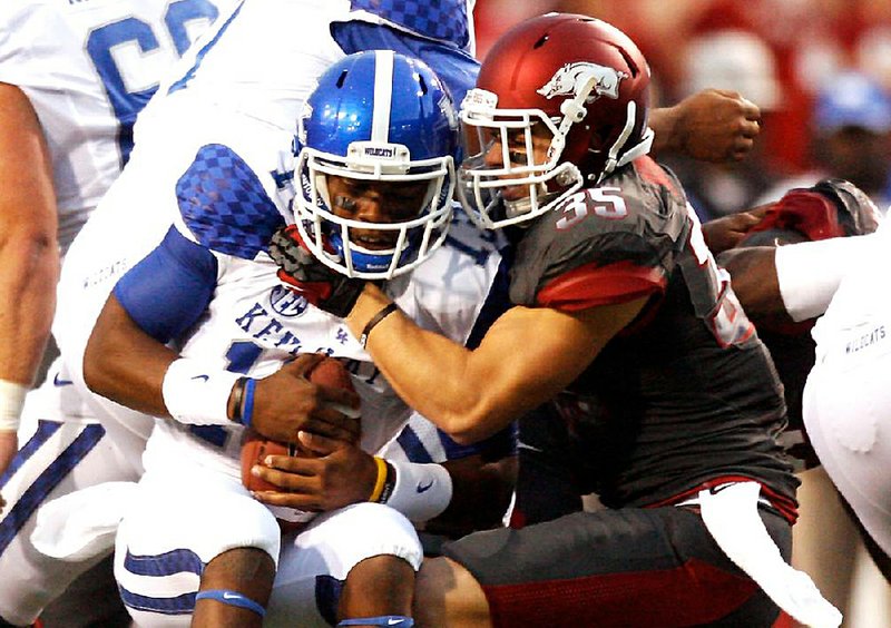 Arkansas safety Ross Rasner (right) sacks Kentucky quarterback Jalen Whitlow in the first quarter of the Razorbacks’ storm-shortened 49-7 victory Saturday at Reynolds Razorback Stadium in Fayetteville. Arkansas had two sacks in the game, which was delayed once in the first half and a second time in the third quarter. During the second stoppage, with 5:08 left in the third quarter, a decision was made to call the game. 