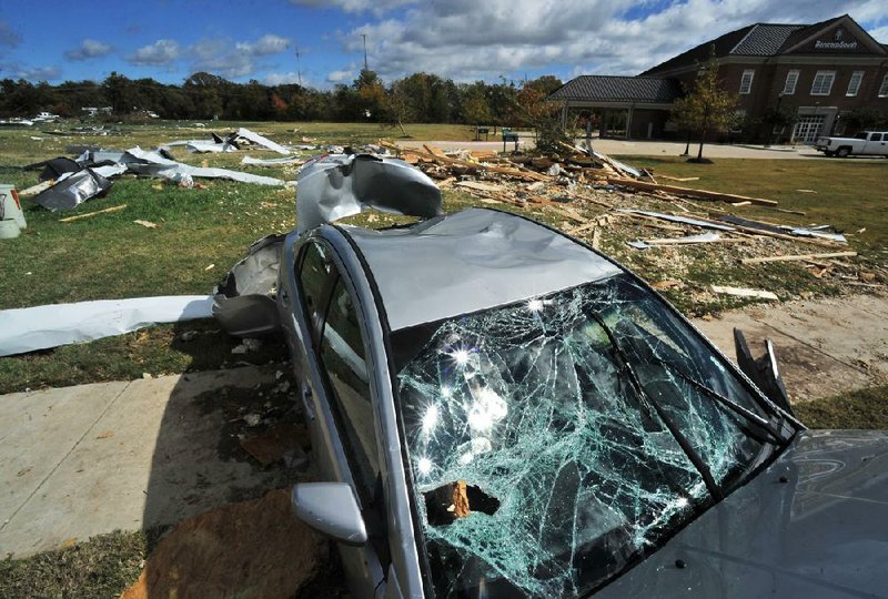 STAFF PHOTO BY MICHAEL WOODS --10/14/2012--  A car sits in the debris from parts of nearby buildings that were damaged when a suspected tornado touched down late Saturday night in Rogers along s 52nd street.   The storm damaged several building and houses in the area and caused damage to hundreds of trees.