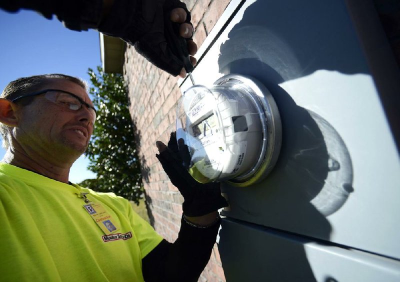 Randy Gregory, a technician with Mueller Service Co., installs an advanced electric meter at a Bentonville home on Thursday. 