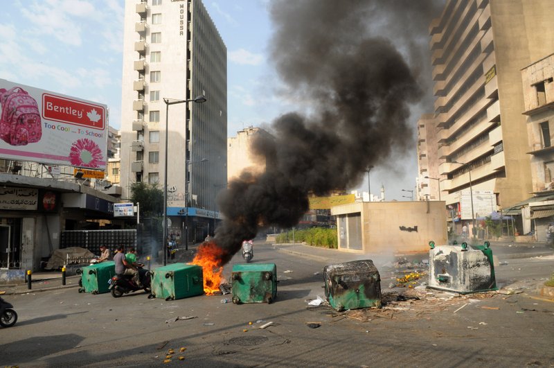 Men on a motorbike navigate burning garbage containers laid by Sunni protesters, angry at the killing of Brig. Gen. Wissam al-Hassan, to block roads, in Beirut, Lebanon, Saturday, Oct. 20, 2012. Lebanese security officials say angry protesters have closed roads around the country to protest the bombing that killed a top security official and seven other people.