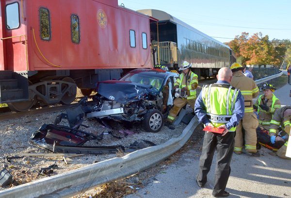 Emergency responders attend to the driver of a vehicle after the car was hit by an Arkansas & Missouri Railroad train Friday morning on Main Street in Johnson. 