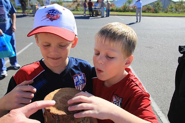 Brandon Patterson, 9 (left), of Mayflower and his twin brother, Carter, count the rings of a pine log Saturday during an open house at the National Weather Service forecast office in North Little Rock. 