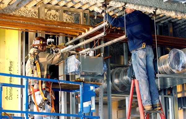 Josh Bunch, left, and Cody Shepherd, both with Multi-Craft in Springdale, work on a ventilation system Thursday inside the new Thompson Street entrance at Northwest Medical Center-Springdale. The emergency room is also being expanded.