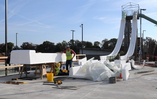 Robert Carminati, right, and Linderson Oliveira work Wednesday on one of the five slides at the aquatic center north of West New Hope Road on South 26th Street in Rogers. The Parks Department’s budget will increase for 2013 because of the opening of the center and sports park, both under construction and slated to open in 2013.
