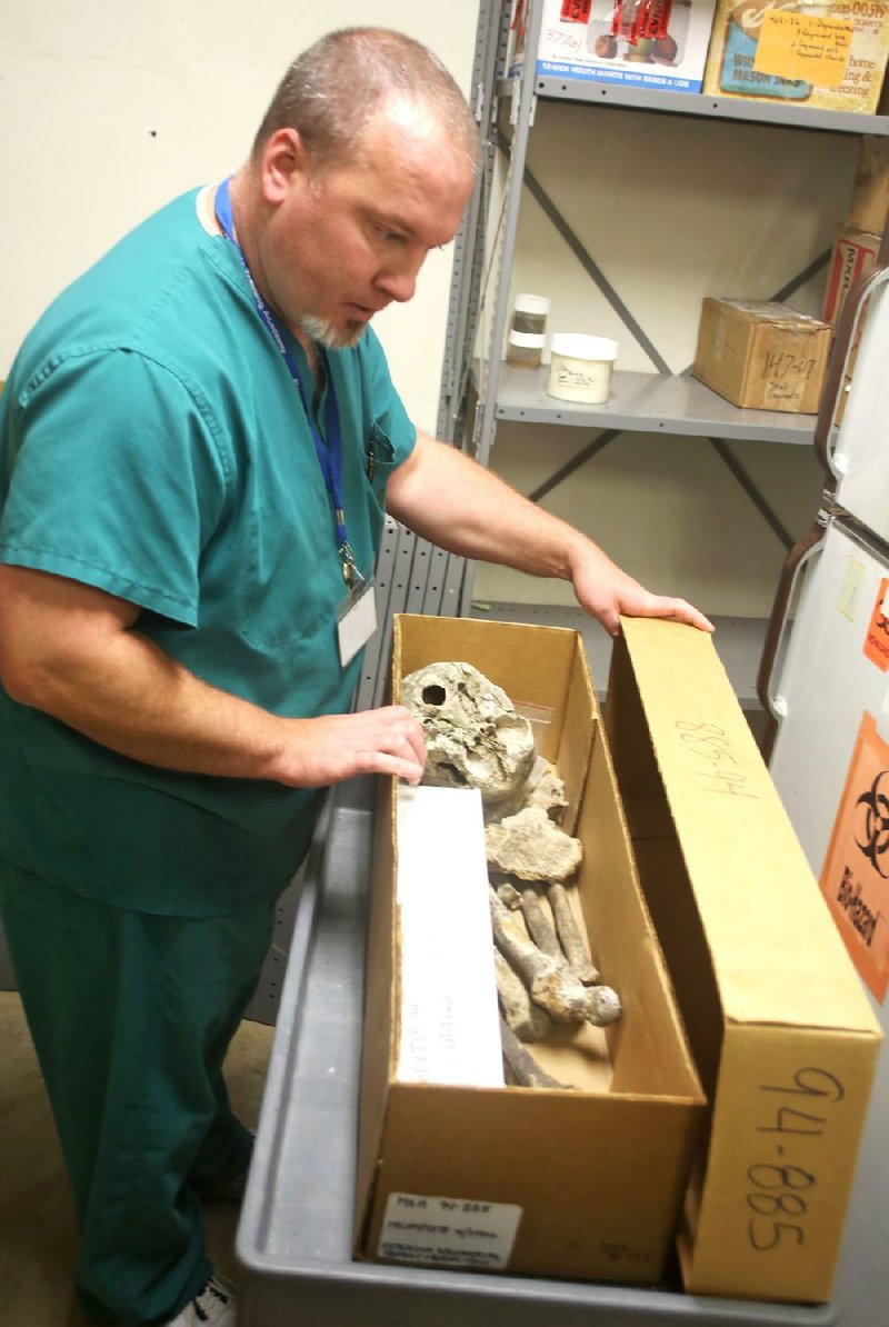 Chris Edwards, who is in charge of unidentified and missing persons at the state Crime Laboratory, examines a box of unidentified remains at the lab. 