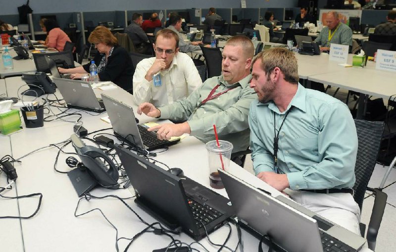 Mike Rutherford (from left), Myles Bennett and Keith Dye, all with Wal-Mart Stores Inc., talk Monday about security and safety plans for stores in the path of Hurricane Sandy in Wal-Mart’s Emergency Operations Center in Bentonville. 