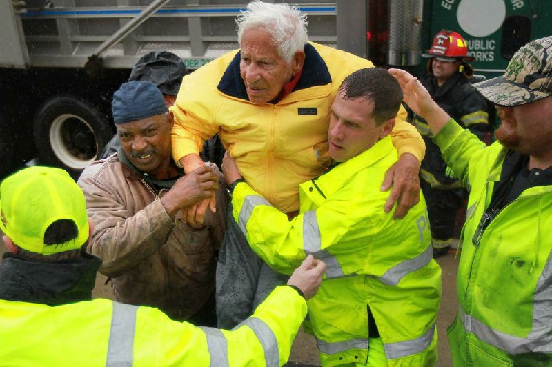 An elderly man is rescued Monday by volunteer firemen in West Atlantic City, N.J. Hurricane Sandy forced the shutdown of mass transit, schools and financial markets, sending coastal residents fleeing, and threatening a mix of high winds and soaking rain. 