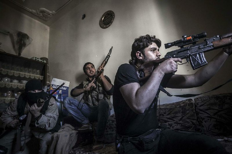 A rebel sniper watches Syrian army positions Monday in the Aleppo Jedida district of Syria. 