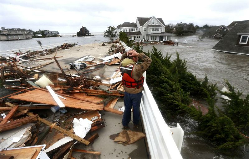 Brian Hajeski of Brick, N.J., looks at the debris of a home that washed up Tuesday on the Mantoloking Bridge in Mantoloking on New Jersey’s northern coastline. 