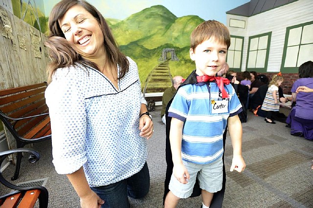 Georgia Meredith (left) is tickled, rather than scared, at the sight of her son, Carter, in a black cape for Halloween at the Old State House Museum. 