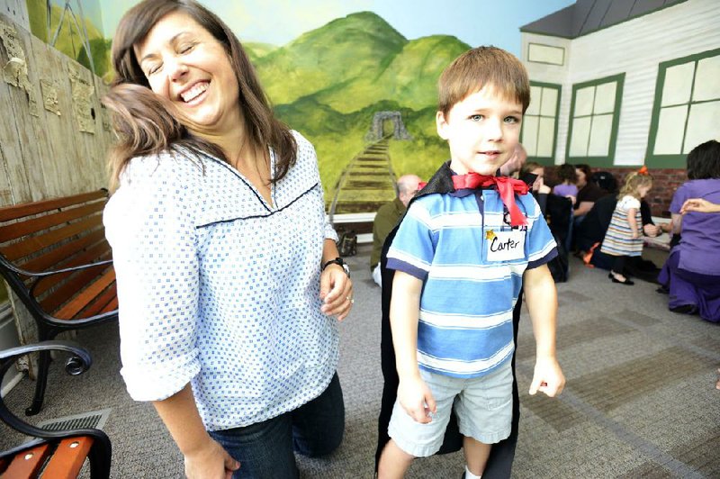 Georgia Meredith (left) is tickled, rather than scared, at the sight of her son, Carter, in a black cape for Halloween at the Old State House Museum. 