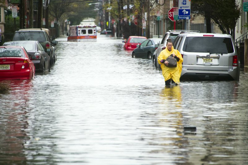 A resident walks through flood water and past a stalled ambulance in the aftermath of superstorm Sandy on Tuesday, Oct. 30, 2012, in Hoboken, N.J.