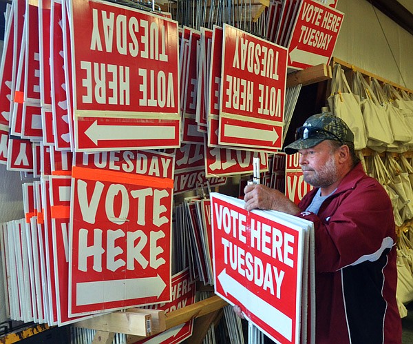FILE - Art Hughes, a poll worker with Washington County’s Election Commission, helps load vote signs from the commission warehouse in Fayetteville.