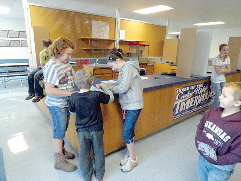 Cord-Charlotte Elementary Student Council members Gloria Morgan, left, and Emily Bull, right, assist kindergartner Aiden Jones as he shows his ID to sign in to vote during the school’s mock presidential election this week.