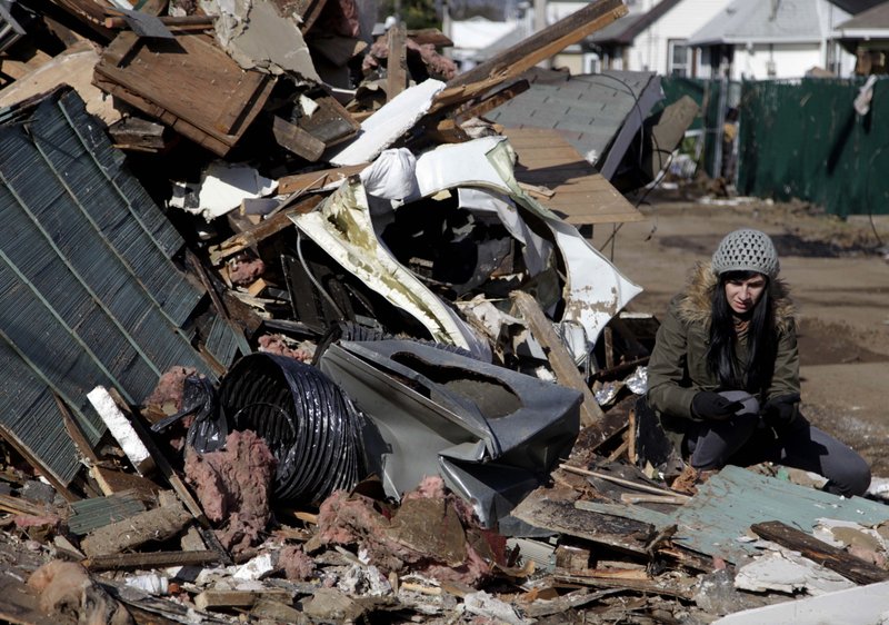 Julie Traina tries to recover some personal items from the destroyed home of her parents in Staten Island, N.Y., Friday, Nov. 2, 2012. Mayor Michael Bloomberg has come under fire for pressing ahead with the New York City Marathon. Some New Yorkers say holding the 26.2-mile race would be insensitive and divert police and other important resources when many are still suffering from Superstorm Sandy. The course runs from the Verrazano-Narrows Bridge on hard-hit Staten Island to Central Park, sending runners through all five boroughs. The course will not be changed, since there was little damage along the route.