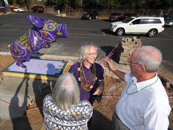Longtime Eureka Springs artist Zeek Taylor, center, is greeted Oct. 4 by friends and patrons Cheryl Moore of Fayetteville, left, and Tom McCoy of Bentonville during the installation for his Pigshibition entry, “The Pig Easy,” at Powerhouse Seafood in Fayetteville. 