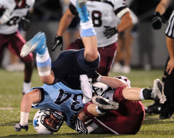 Neal Parson, right, Springdale High, rolls Tucker Lee of Springdale Har-Ber over on a tackle Friday at Jarrell Williams Bulldog Stadium in Springdale. The cross-town rivalry game was the last for the regular season games this year and was senior night for Har-Ber. 