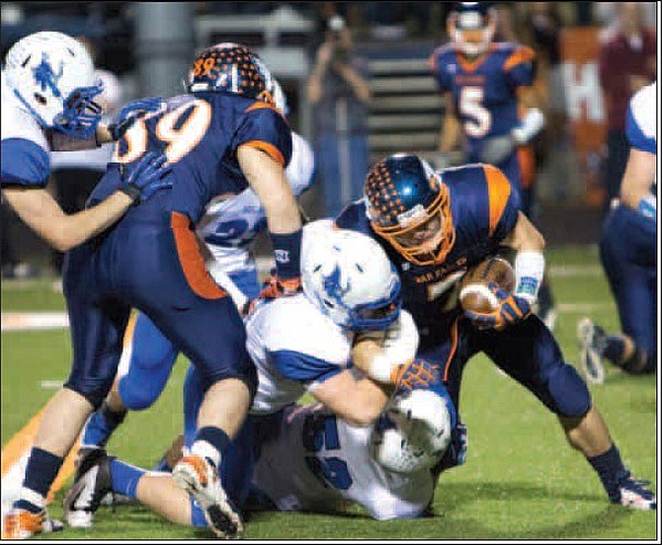 Brandon Gates, right, a Rogers Heritage running back, fights for extra yards while being brought down by Rogers High defensive lineman Alex McClung during Friday’s game at Gates Stadium in Rogers. 