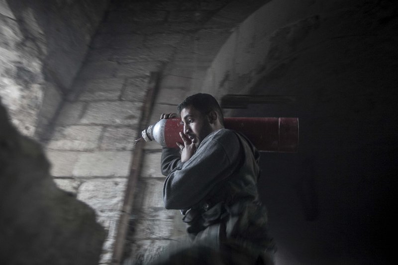 In this Saturday, Nov. 03, 2012 photo, a rebel fighter carries an improvised explosive device as they try to repel a coordinated attack using mortar, tank and aerial artillery fire carried out by loyalists to President Bashar Assad in the Jedida district of Aleppo, Syria.