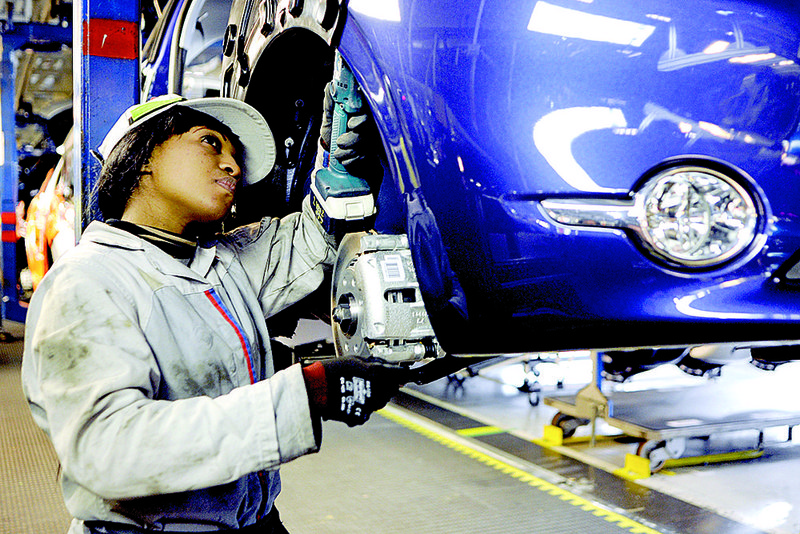 An employee works under the wheel arch of a Peugeot 208 at Peugeot Citroen’s Poissy auto assembly plant in Paris earlier this year. 