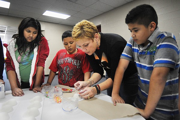 Jeanette Arnhart, a student at the University of Arkansas, shows students at J.O. Kelly Middle School how to decorate sugar skulls during a lesson on the Day of the Dead, a celebration in central and southern Mexico on Nov. 1-2. Arnhart is working with other university students in the Latino Youth Biliteracy Program, an after-school program in its second semester at the school. 