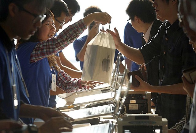An Apple Inc. employee hands an iPad mini to a customer on Friday in Hong Kong. Apple Inc. said Monday that it sold 3 million units of its iPad mini and fourth-generation iPad in the first weekend of sales. 