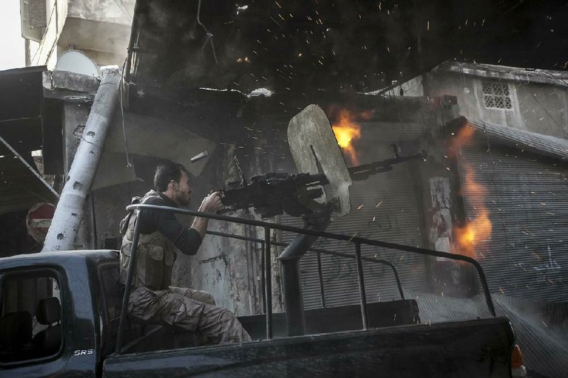 A rebel fighter fires a machine gun toward Syrian troops hiding in a building during heavy clashes Sunday in the Jedida district of Aleppo, Syria. 