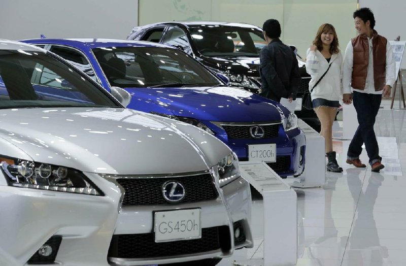 A couple look at Lexus models displayed at a Toyota Motor Corp. showroom Monday in Tokyo. Toyota said its quarterly profit tripled despite a sales slump in China. 