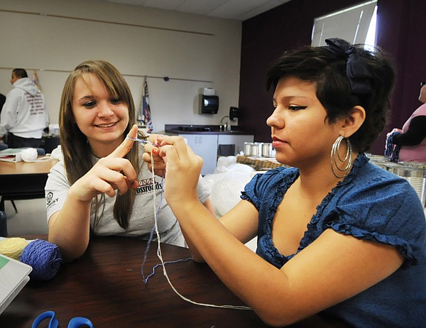 McKensie Collins, a sophomore, left, and Reina Castillo, a junior, work on making a bracelet in their craft class at the Rogers Annex. Teachers with the group Reality Check work with the students and are helping them put on a bazaar in December to sell some of the handmade quilts, hand warmers and scarves. 