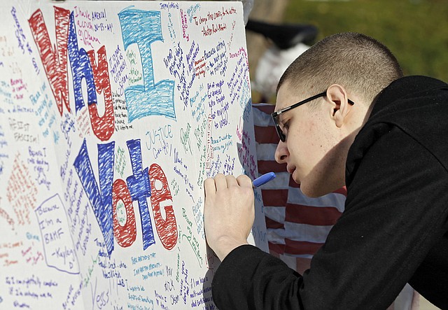 Sophomore David Ganjehlou signs a "Why I Vote" poster after voting at Oberlin College in Oberlin, Ohio, on Tuesday, Nov. 6, 2012. 