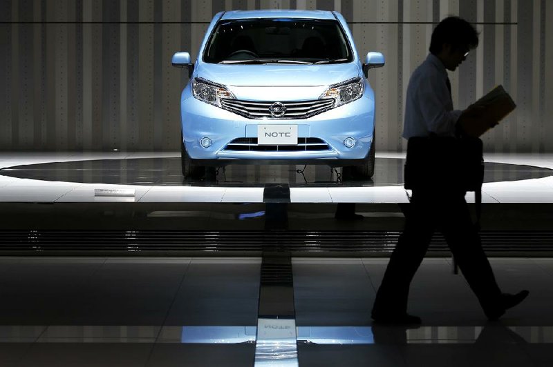 A visitor passes a Nissan Motor Co. Note on display Tuesday at company headquarters in Yokohama City, Japan. Nissan reported a profit of $1.3 billion in the July-to-September quarter. 