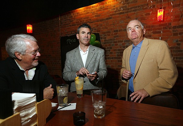 Patric Brosh, from left, Marshall Ney and Jay Allen, all with Keep Dollars in Benton County, sit around the bar at Table Mesa Bistro in Bentonville on Tuesday while watching voting results. The Keep Dollars in Benton County group helped get the issue on the ballot to legalize retail alcohol sales in Benton County. 