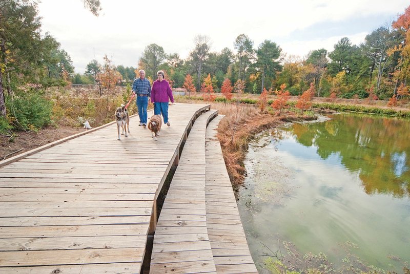 Dave, left, and Doris Bounds of Conway walk dogs along the trail in the Hendrix Creek Preserve. The preserve provides storm-water management for the surrounding watershed and is being enhanced by extending existing walking trails.