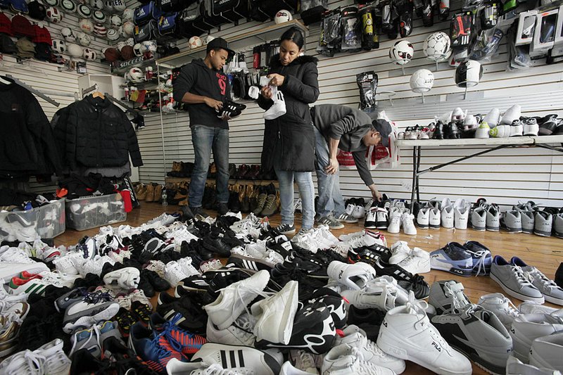 A shopper (center) picks through water-damaged shoes Tuesday in Sneaker Town in the Coney Island section of New York. 