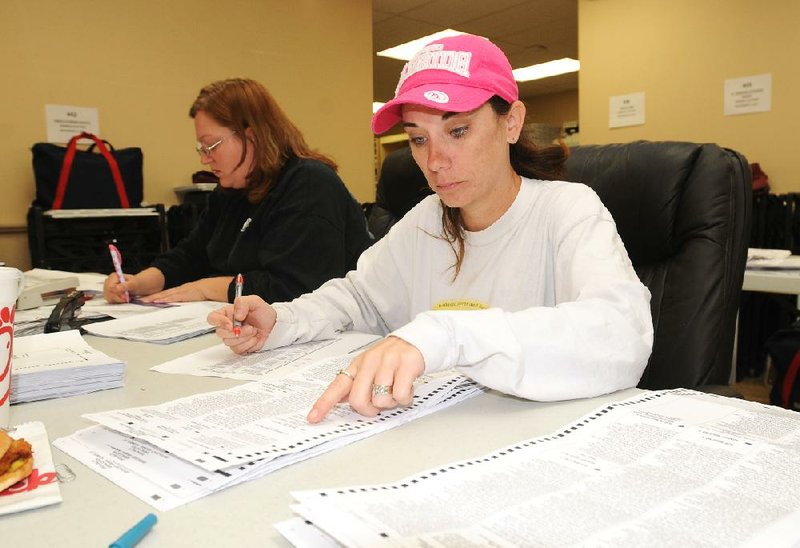 Jamie Fields (left) and Serena Green count paper ballots by hand Wednesday at the Benton County Election Commission offices in Bentonville. 