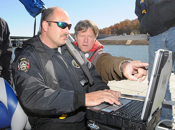 John De Mille, right, marketing, sales and operations director for Marine Sonic Technology, teaches Sgt. Rick Holland and other members of the Benton County Sheriff’s Office how to use the computer software Wednesday that communicates with a sonar device used to map the bottom of open water areas at Prairie Creek Marina at Beaver Lake in Rogers. The side scanning sonar can detect items, or bodies, that need to be recovered from the lake bottom up to about 50 meters on either side of the tow fish. The equipment supplements the county Dive Team’s effort by finding bodies faster and identifying obstructions that could endanger divers attempting to recover people that have drown in the lake.